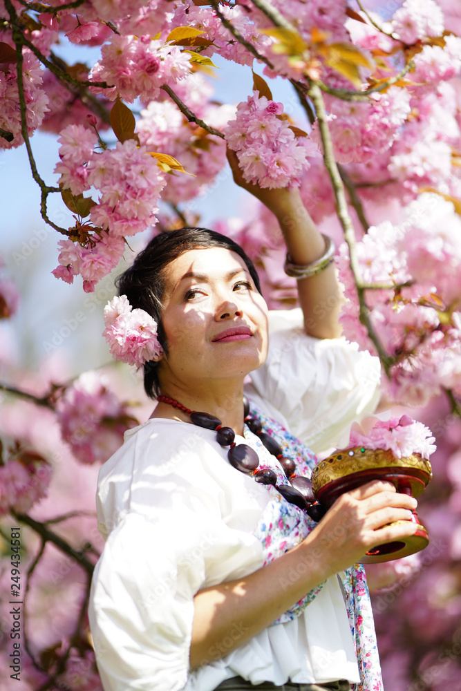 Fototapeta premium Femme asiatique cheveux courts au milieu des fleurs de sakura