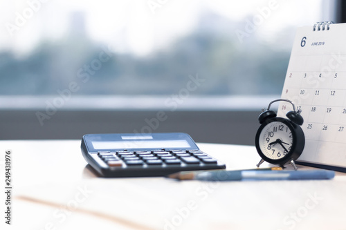 Alarm clock calculator and calendar on desk with city view background
