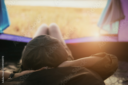Young woman lying in tent or sleeping on bag with a sunset view on mountains and lake, Camping with Sunset in base camp, One Activity Relaxing in summer