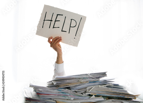 Person under a pile of papers with a hand holding a sign of help. Accounting.