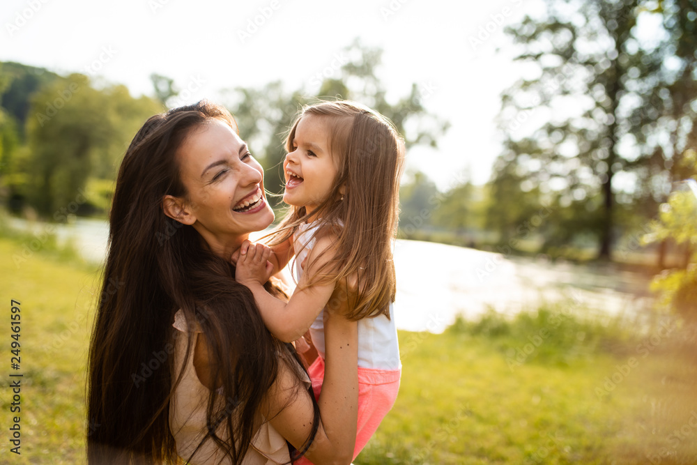 Woman with bright smile holding her daughter Woman with bright smile holding her daughter