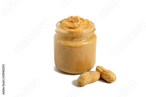 Peanut butter in a glass jar with peanuts isolated on white background.  A traditional product of American cuisine.