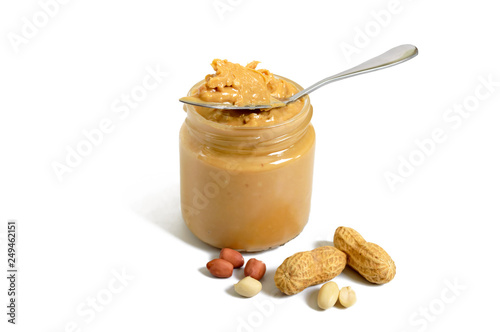 Peanut butter in a glass jar and a whole peanut isolated on white background.  A traditional product of American cuisine.