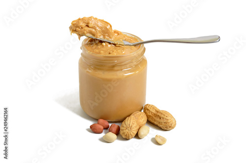 Peanut butter in a glass jar and a whole peanut isolated on white background.  A traditional product of American cuisine.