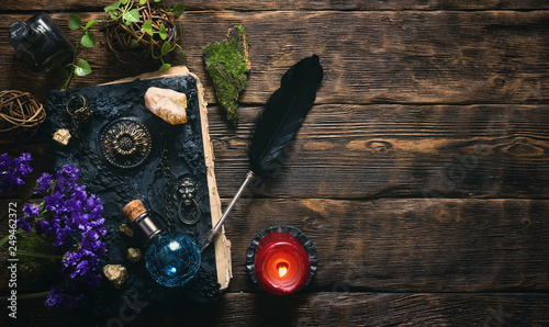 Spell book, magic potions and other various witchcraft accessories on the wizard table background with copy space.