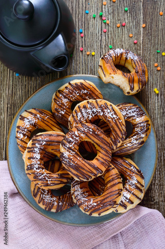 Homemade classic donuts with chocolate and coconut flakes on a wooden background.Top view. Flat lay