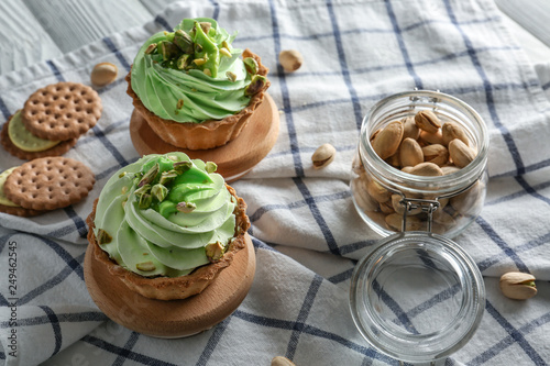 Tasty pistachio tartlets with nuts on table