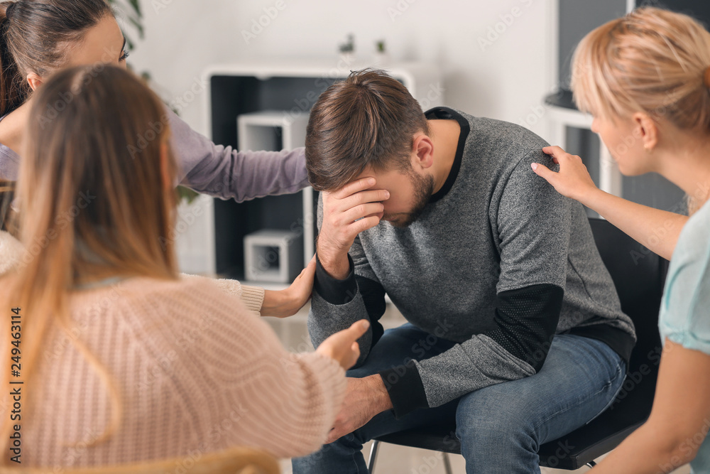 Group of people calming their friend indoors Group of people calming their friend indoors