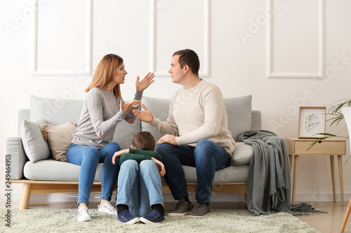 Sad little boy with his quarreling parents at home