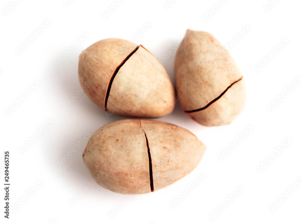 Three unpeeled pecan nuts in shell, with cracks, isolated on white