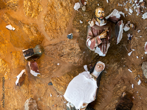 Broken vandalized plaster catholic plaster statues in the ground photo