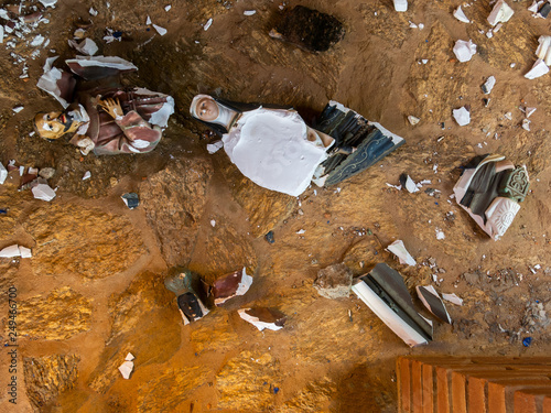 Fotografi Broken vandalized plaster catholic plaster statues in the ground