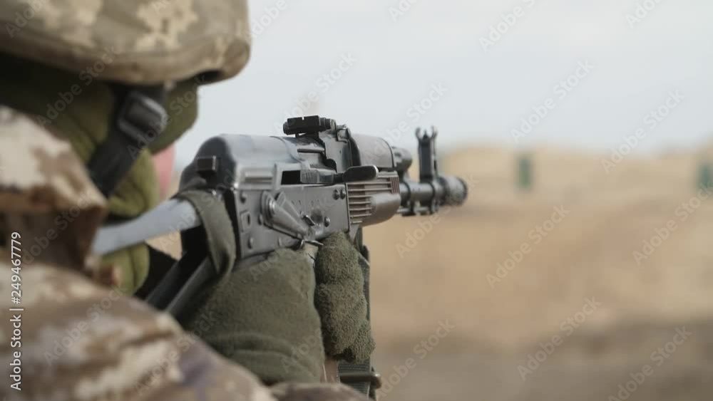 Officer shooting from AK 74 in khaki uniform in a large field in slo-mo Officer shooting from AK 74 in khaki uniform in a large field in slo-mo