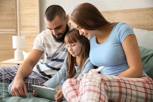 Happy family with tablet computer on bed at home