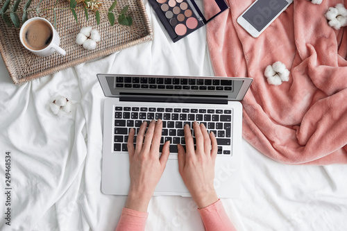 Beauty blogger working with laptop on bed
