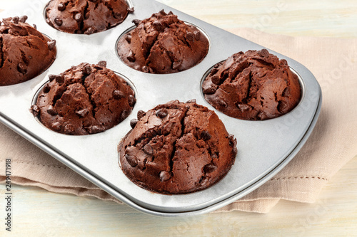 Chocolate muffins in a pan on a light background with copy space