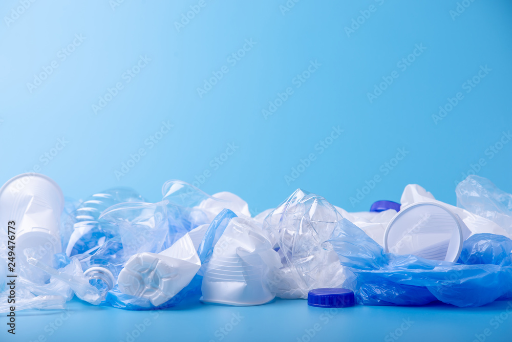 Used clean plastic garbage in a pile. Bottles and bags on blue background. Concept of waste sorting Used clean plastic garbage in a pile. Bottles and bags on blue background. Concept of waste sorting