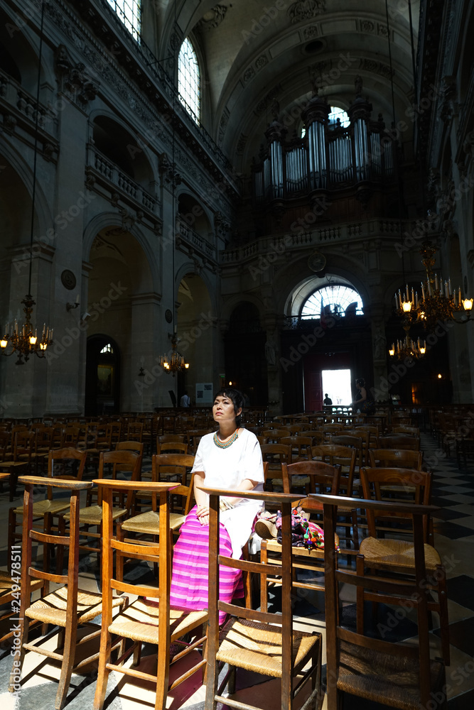 Femme assise priant dans une église, éclairée par la lumi§re du soleil