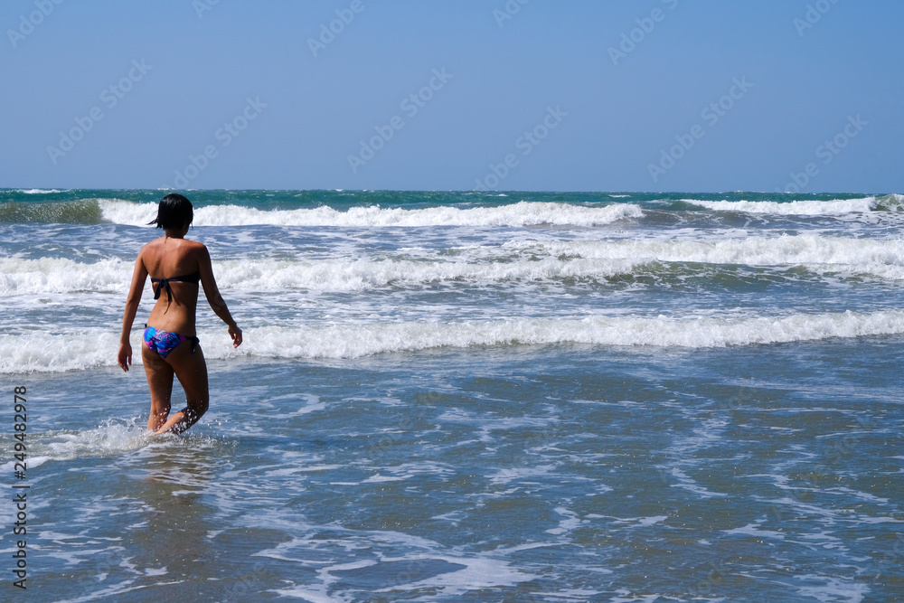 girl walks into the water on the beach