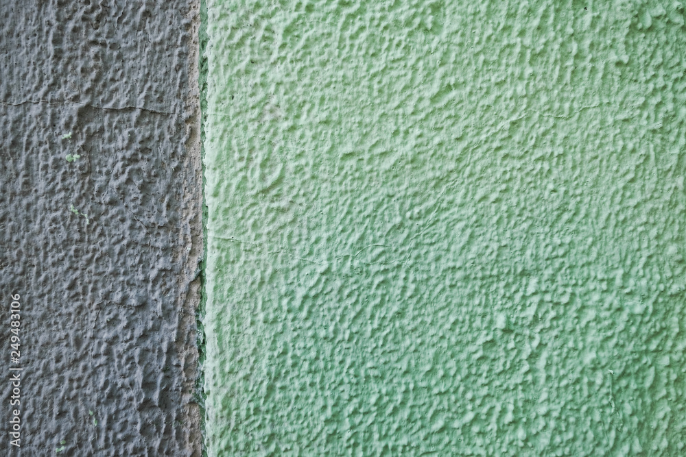Textured stone green wall. Peeling paint on the gray concrete surface. Textured stone green wall. Peeling paint on the gray concrete surface.