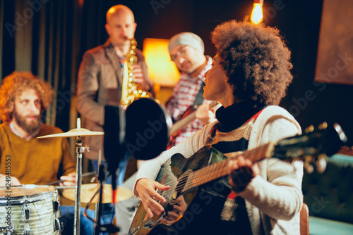 Photography Mixed race woman singing and playing guitar while sitting on chair