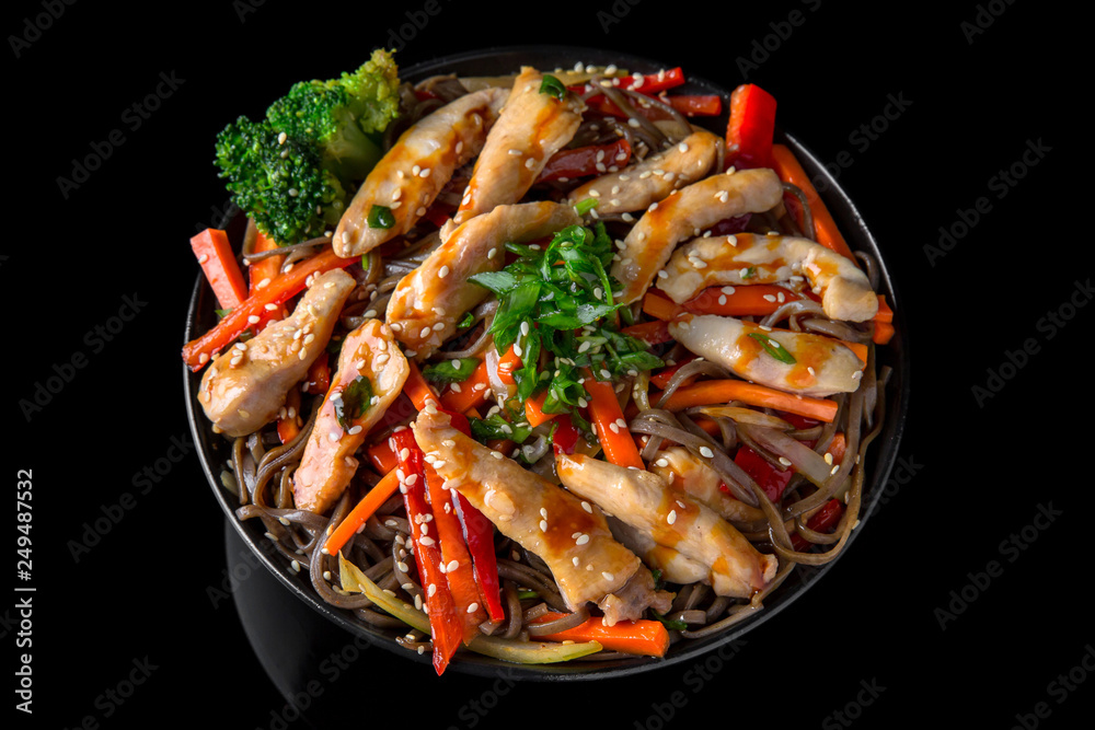 Soba Noodles (buckwheat) with chicken and vegetables: carrots, sweet peppers, broccoli on a black background. Sushi menu. Japanese food