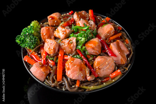 Soba Noodles (buckwheat) with salmon  and vegetables: carrots, sweet peppers, broccoli on a black background. Sushi menu. Japanese food