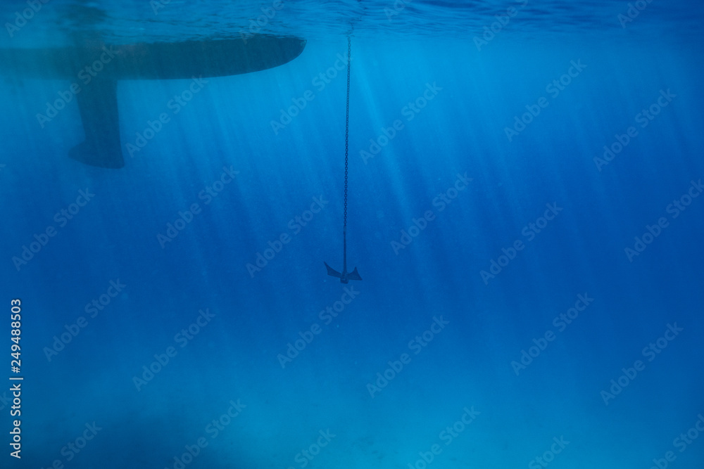 Sailing boat with the anchor going down, blue ocean under water photography with a sailing ship on it 