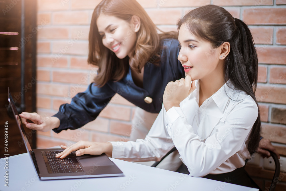 Two young business women are analytics information on laptop screen, business meeting Two young business women are analytics information on laptop screen, business meeting