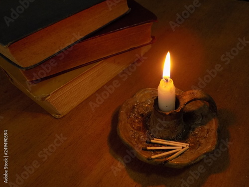 Vela encendida con libros antiguos sobre una mesa