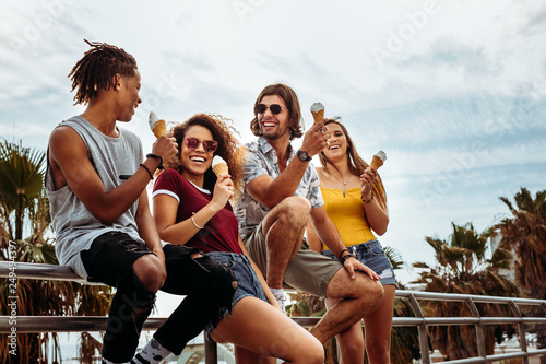 Cheerful buddies eating ice-cream outdoors