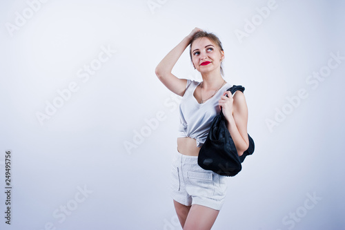 Amazing fit sexy body brunette caucasian girl posing at studio against white background on shorts and top with black sport bag.