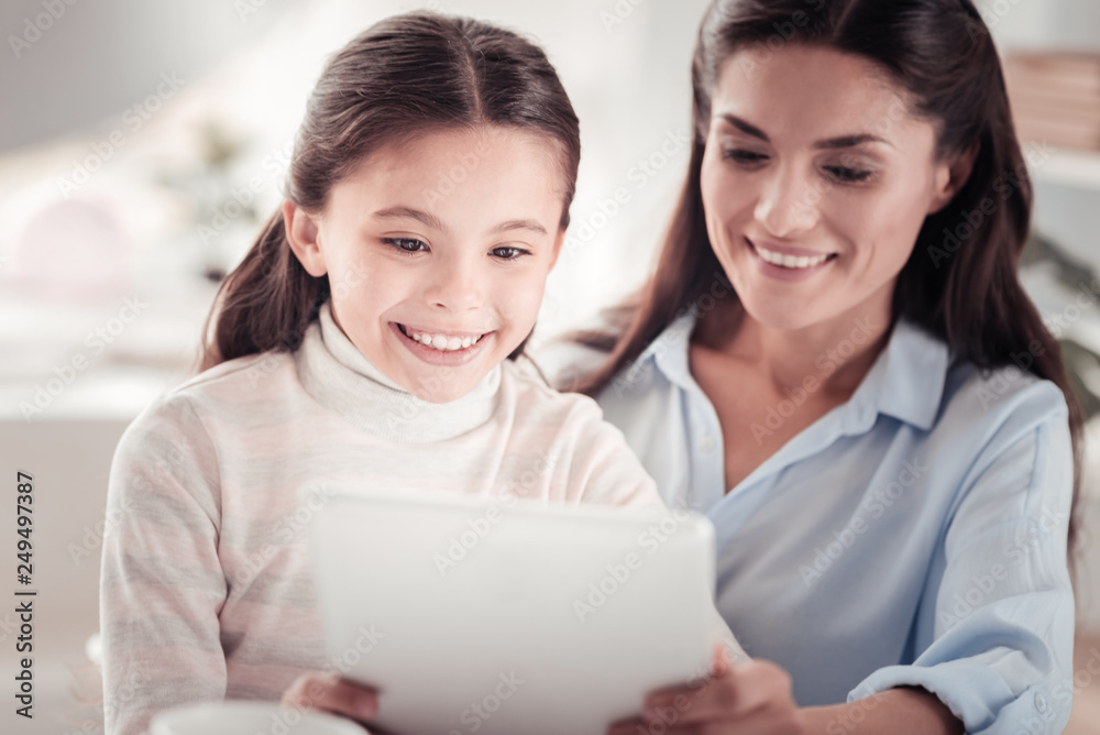 Adorable dark-eyed daughter watching movies with mother Adorable dark-eyed daughter watching movies with mother