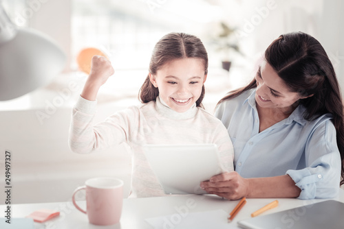 Little charming schoolgirl feeling adorable speaking with father via internet