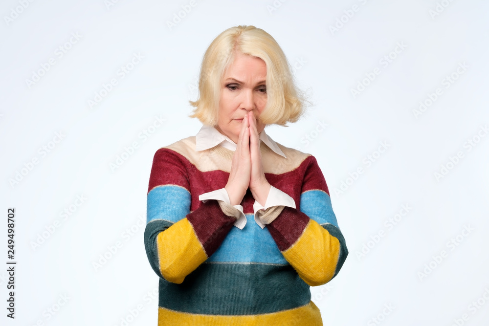 Φωτογραφία Senior blonde woman pressing palms together, having mournful facial expression