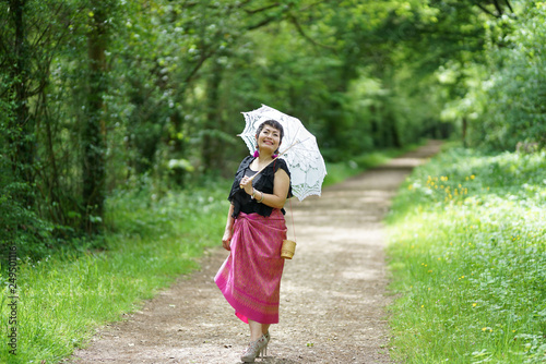 Femme à l'ombrelle blanche en habit traditionnel Thaï se promenant dans la forêt © Phil Jobs