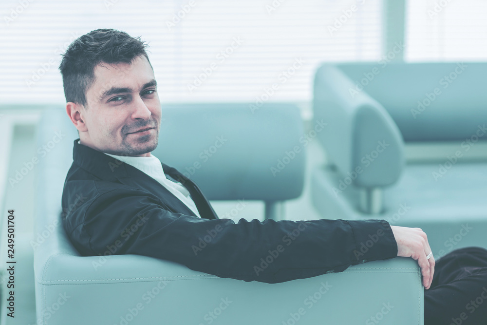 successful businessman sitting on a chair in the lobby of the modern office .the photo has a empty space for your text successful businessman sitting on a chair in the lobby of the modern office .the photo has a empty space for your text
