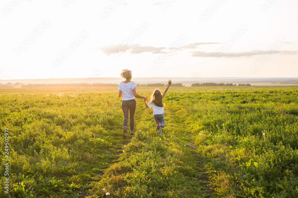Family, summer and holiday concept - little daughter and mother run in the summer field Family, summer and holiday concept - little daughter and mother run in the summer field