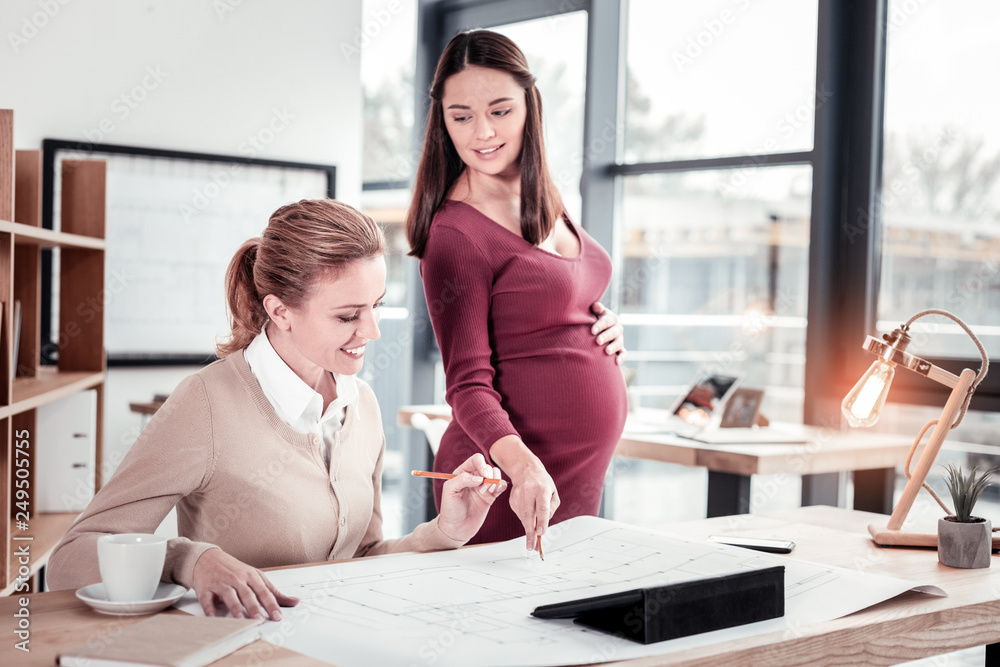 Prosperous attentive chef assisting her employee during work in office Prosperous attentive chef assisting her employee during work in office