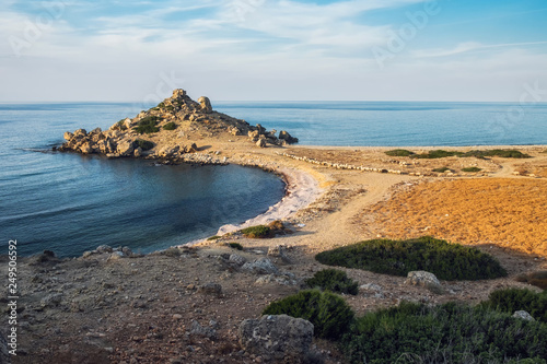 Small Alagadi beach panorama with peninsula and dry pasture with grazing sheep