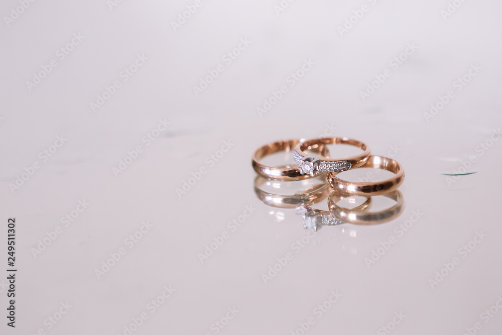 3 wedding gold rings on the white background glass with water drops . Wedding. Diamonds. 3 wedding gold rings on the white background glass with water drops . Wedding. Diamonds.