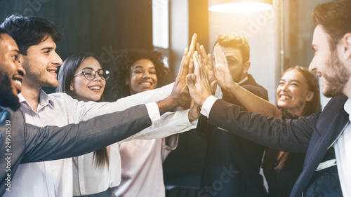 Happy multiracial business team giving high fives photo