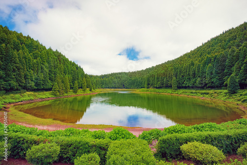 Fototapeta Naklejka Na Ścianę i Meble -  Small lake called Lagoa das Empadadas in Portuguese, surrounded by green forest, located on Sao Miguel island of Azores, Portugal.