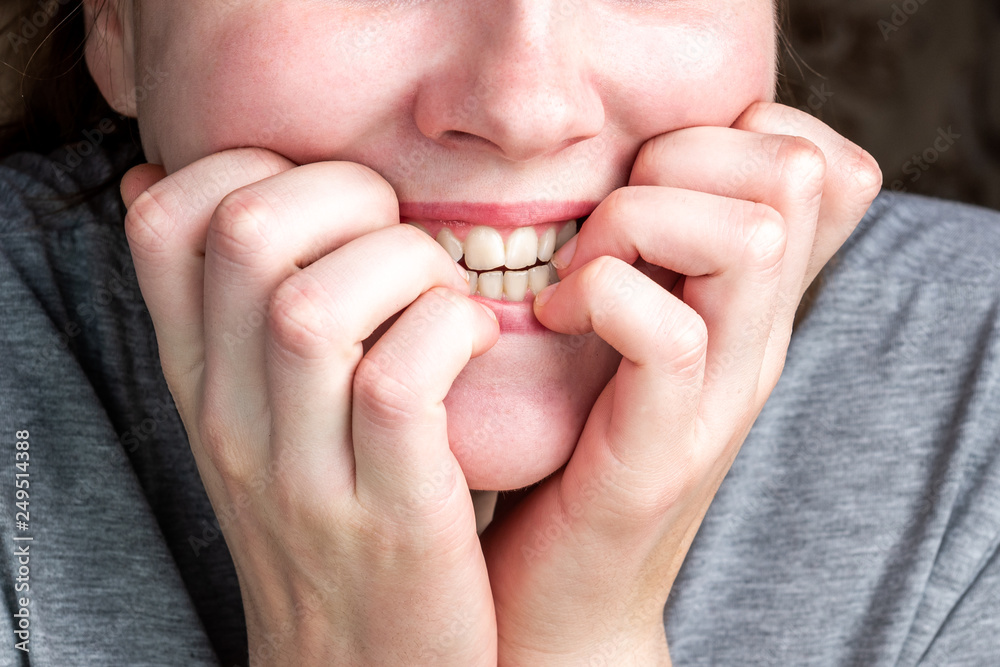 Fototapeta premium Close up of female biting her nails. 