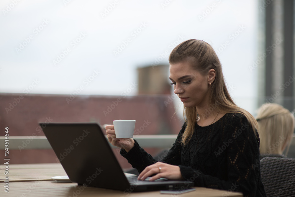 Young beautiful woman using laptop and drinking coffee Young beautiful woman using laptop and drinking coffee