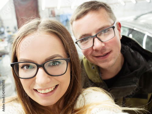 Cute funny blond-haired guy and girl with glasses in the garage