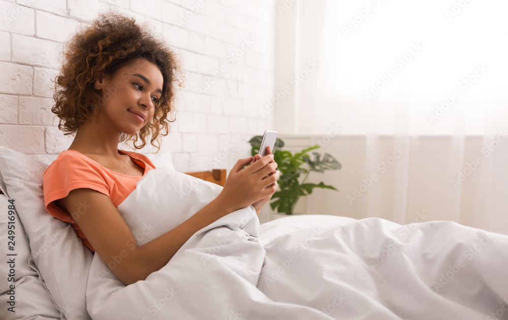 Woman checking social apps on smartphone in bed Woman checking social apps on smartphone in bed