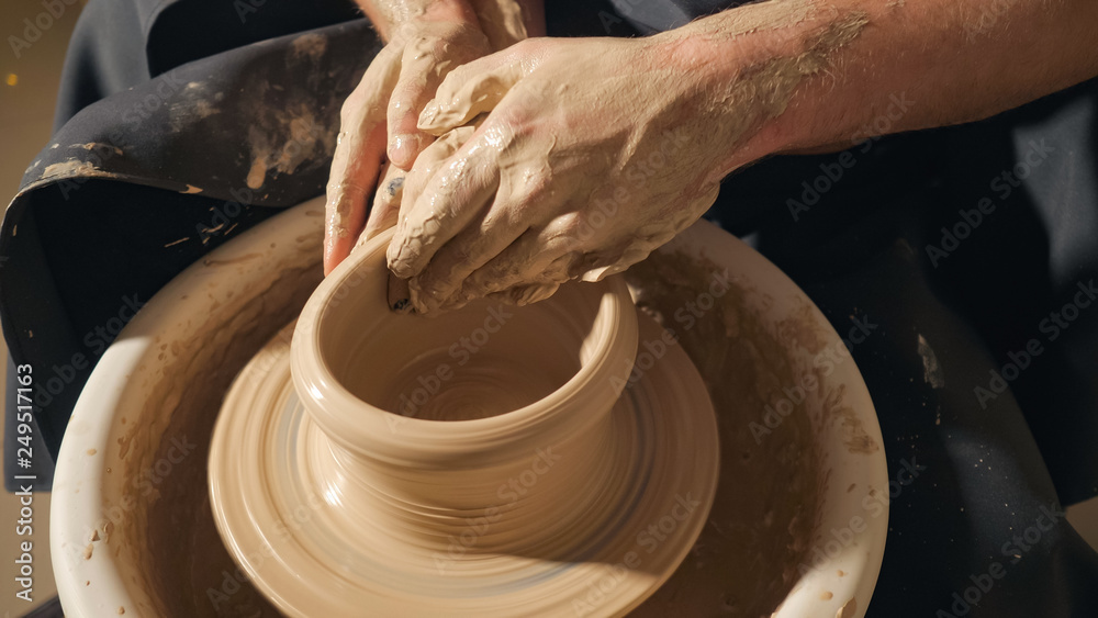 Two intertwined hands form a pot of clay on a potter's wheel. A male hand helps a woman's hands shape a clay shape. Two intertwined hands form a pot of clay on a potter's wheel. A male hand helps a woman's hands shape a clay shape.