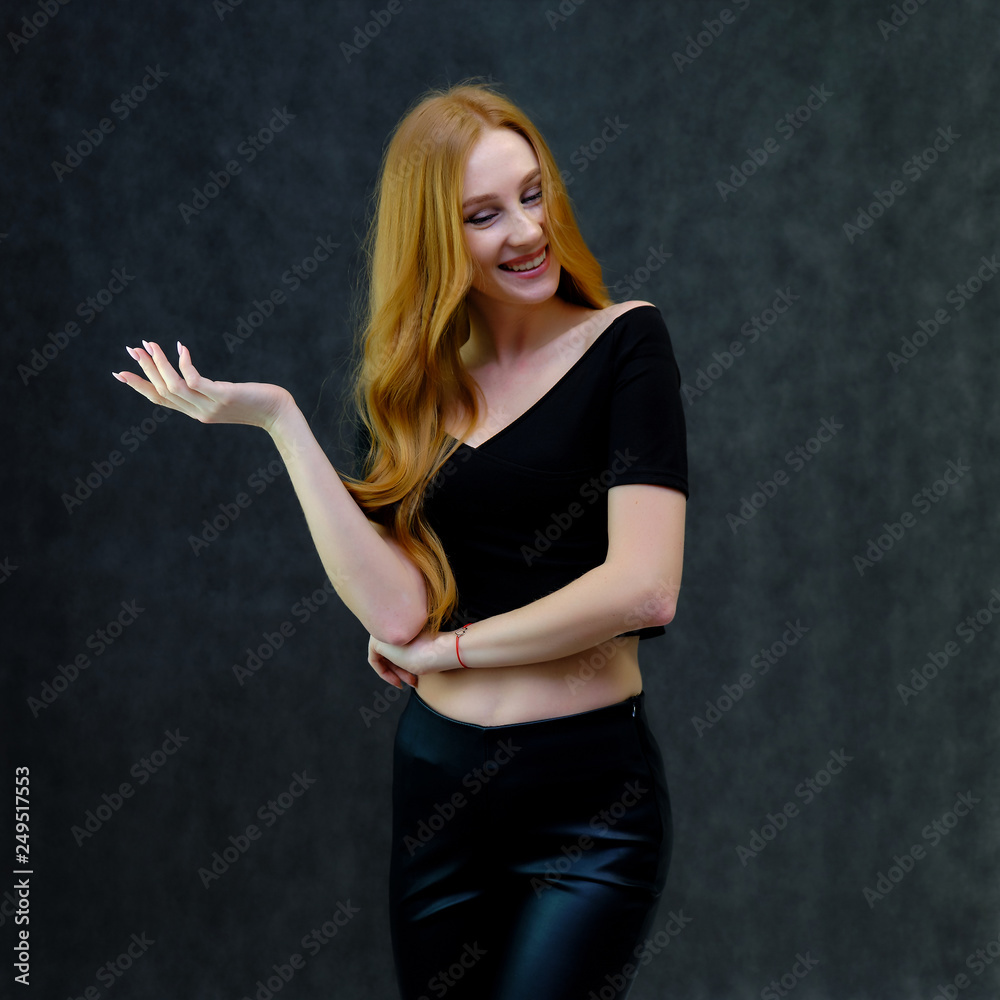 Concept portrait of a cute beautiful red-haired girl talking on a gray background in the studio Concept portrait of a cute beautiful red-haired girl talking on a gray background in the studio