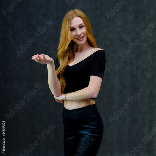 Concept portrait of a cute beautiful red-haired girl talking on a gray background in the studio